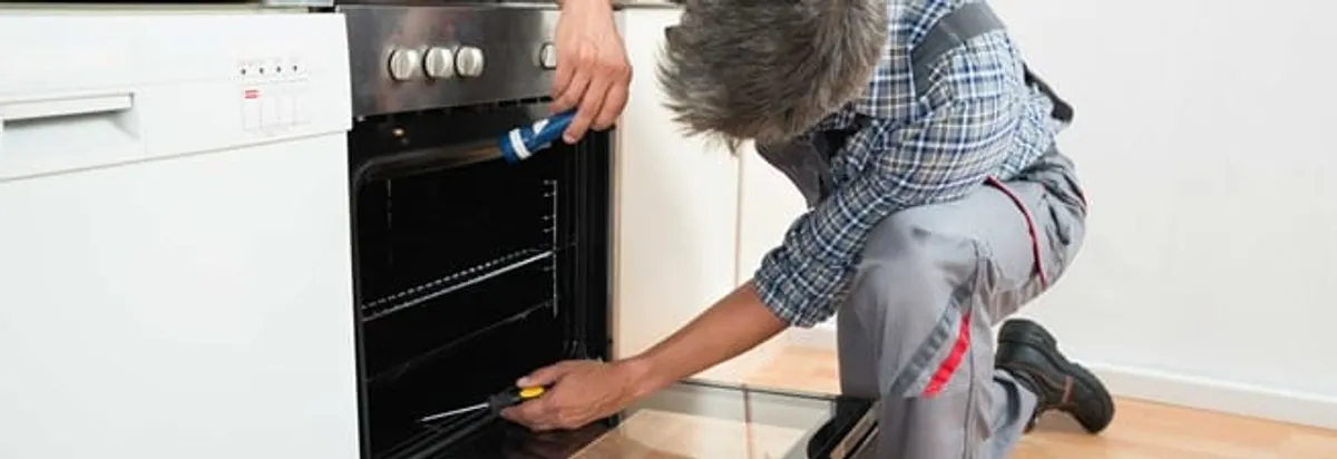Oven repair technician inspecting and servicing an electric oven in Atlanta, GA