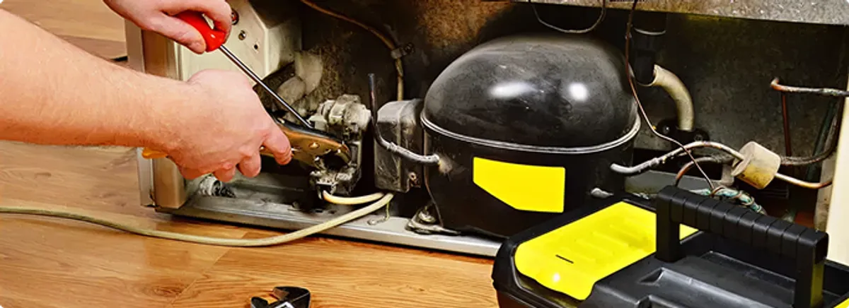 Refrigerator repair technician fixing the compressor and wiring in Atlanta, GA